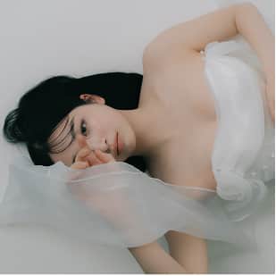 白い布をまとい、穏やかな表情で横たわる女性のポートレート。