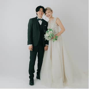 新郎新婦が笑顔で寄り添い、ホワイトバックグラウンドで撮影されたウェディング写真。